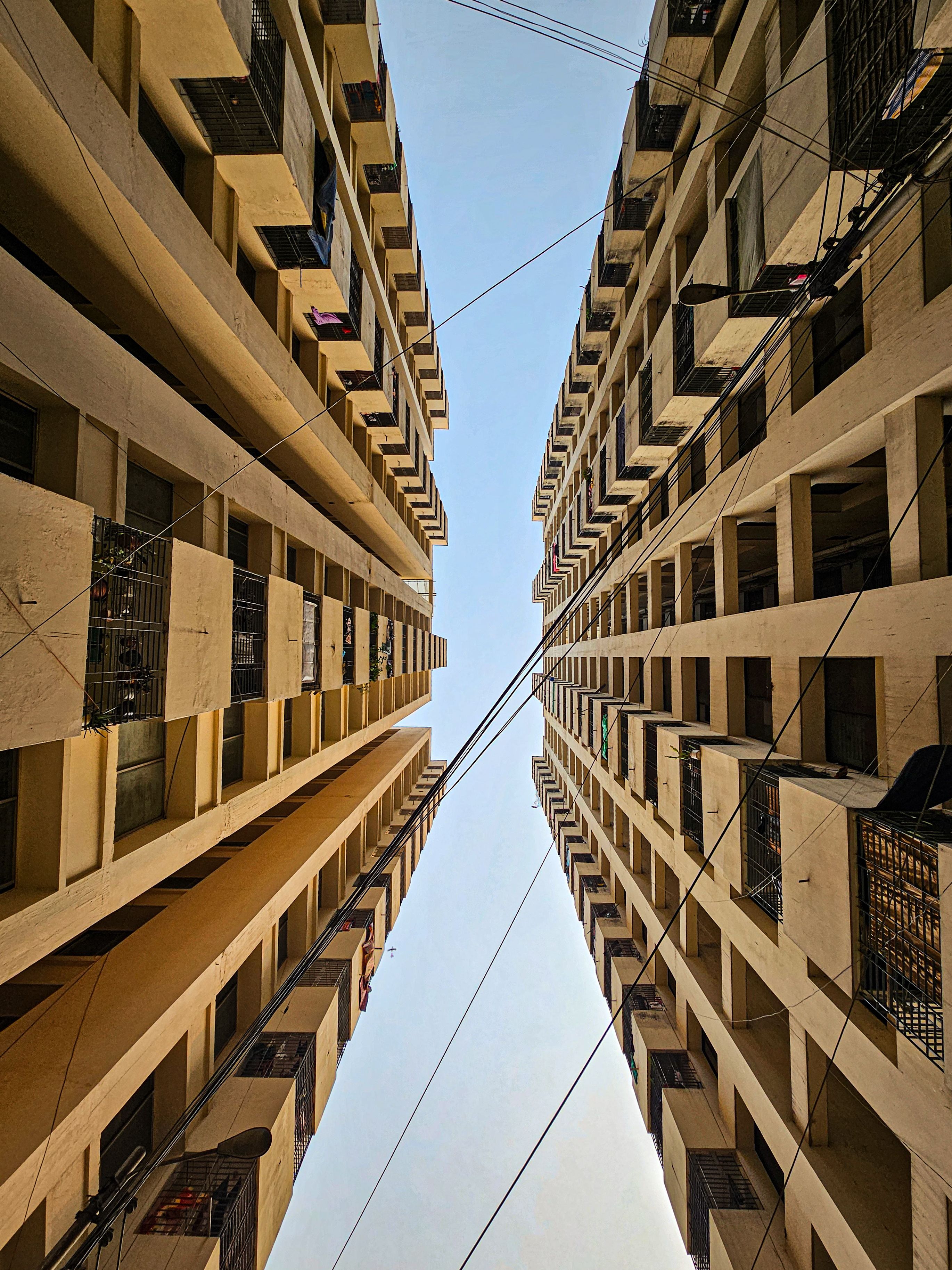 Dramatic perspective of two tall urban residential buildings creating a symmetrical view against the sky.