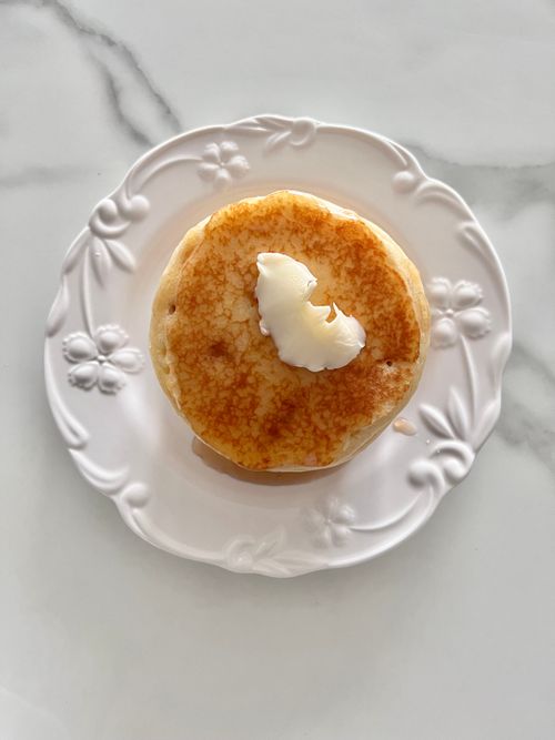 Free Delicious fluffy pancake topped with butter on a decorative white plate. Stock Photo
