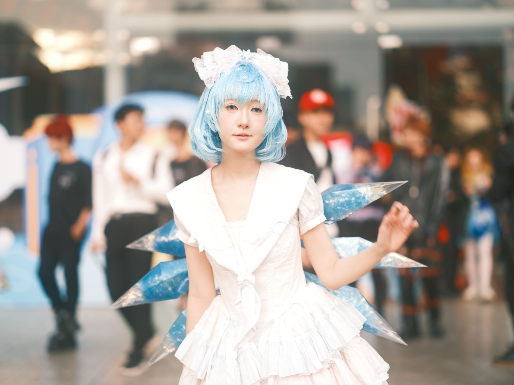 A cosplayer in a white and blue costume poses at a lively event in Vietnam.
