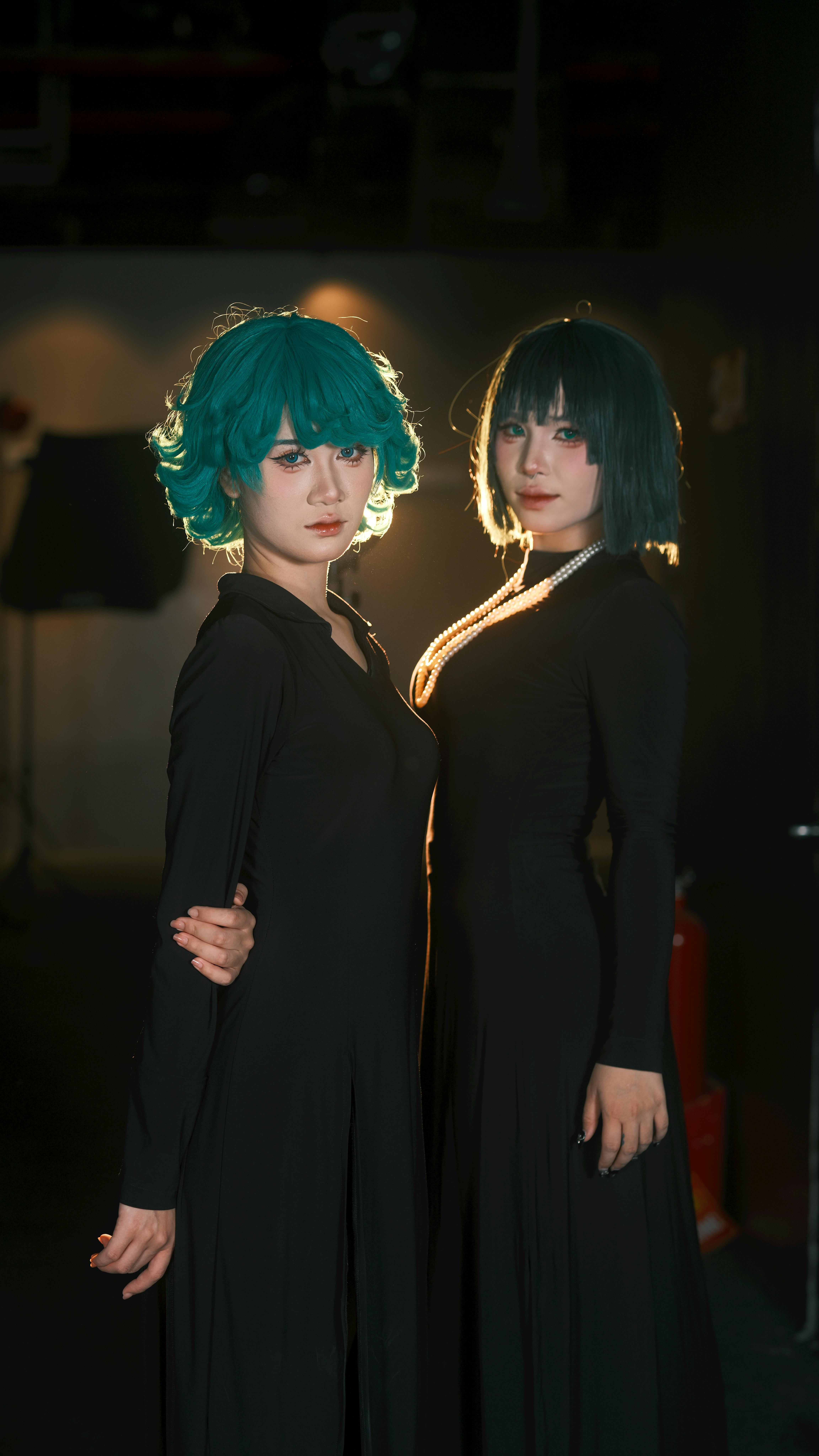 無料 ドラマチックな室内空間で、色鮮やかな髪をした二人の女性が、エレガントな黒いドレスを身にまとっている。 写真素材