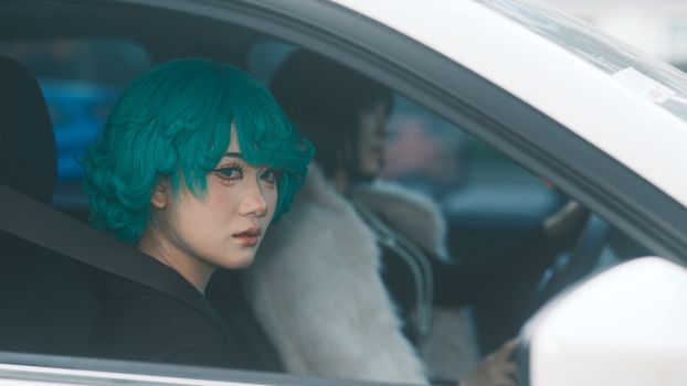 Stylish portrait of a woman with turquoise hair sitting in a car in Vietnam