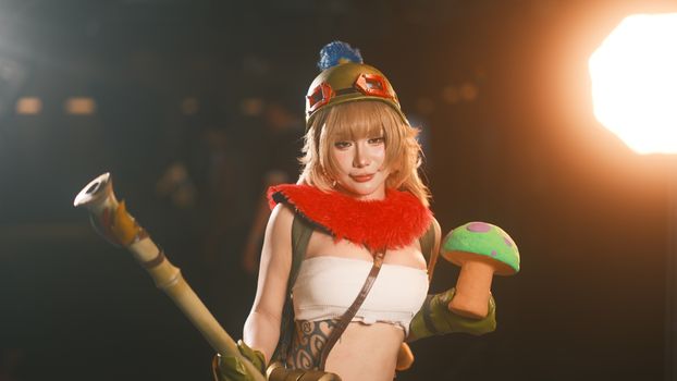 Female cosplayer in vibrant costume holding a toy prop, showcasing charismatic character portrayal.