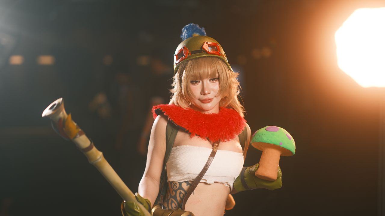 female cosplayer in vibrant costume holding a toy prop showcasing char