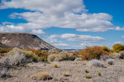 Free Expansive desert terrain under a bright blue sky with scattered clouds. Stock Photo