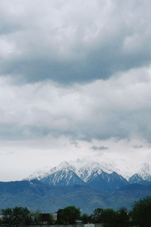 Free Scenic view of snow-covered mountains with a dramatic cloudy sky, perfect for travel and nature themes. Stock Photo