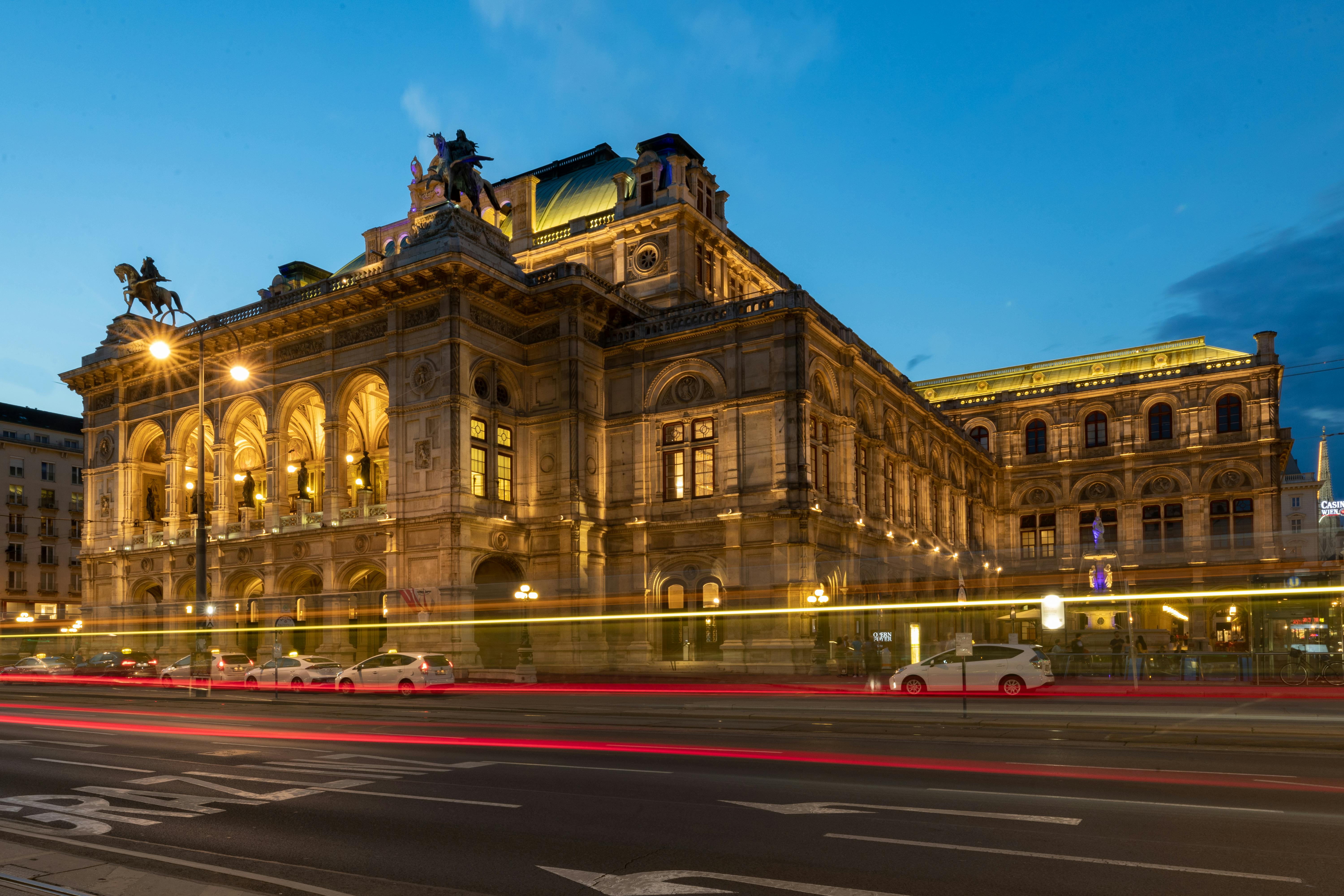 Stunning evening view of Vienna's Opera House illuminated with light trails on the street.