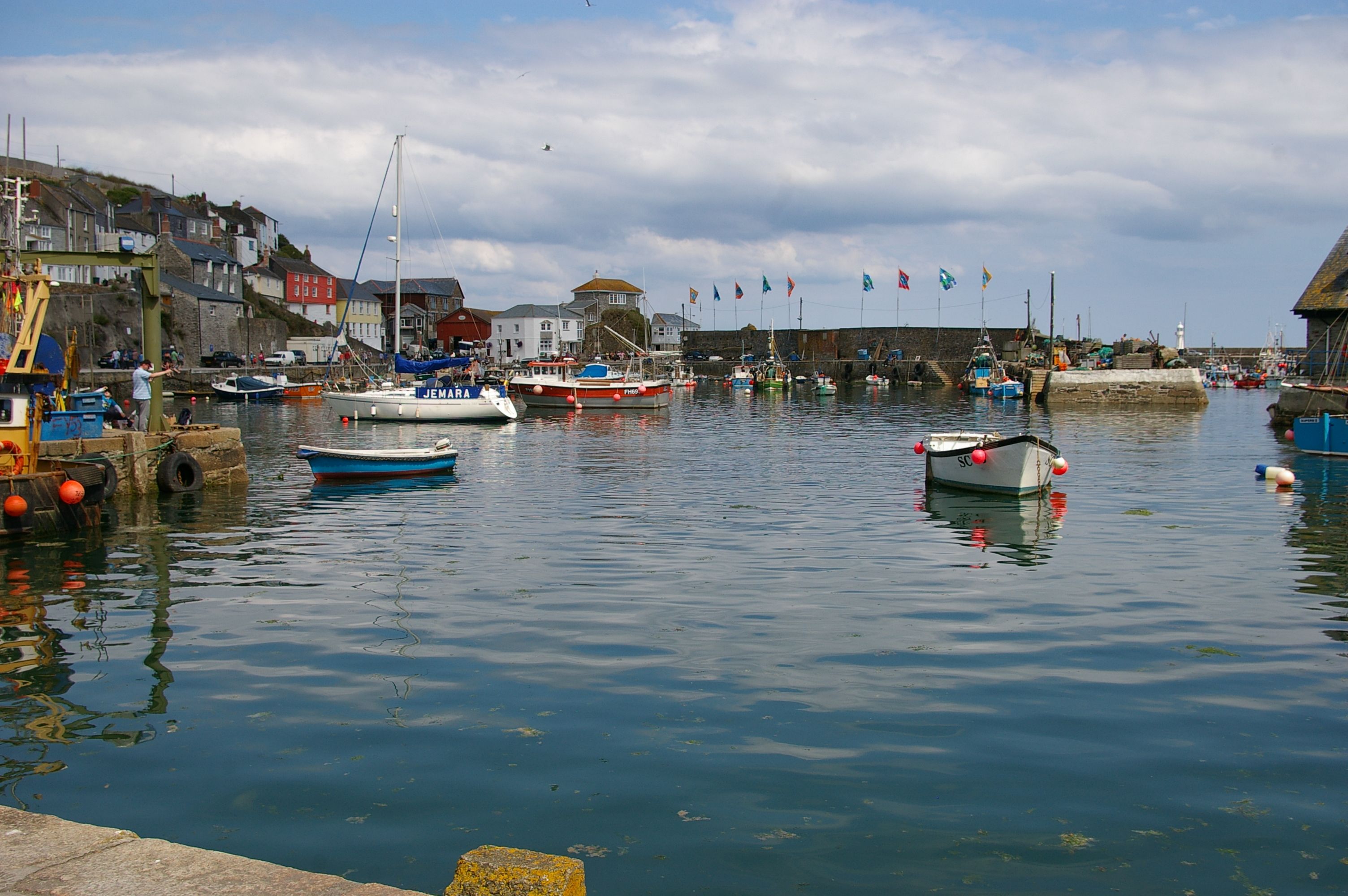 Peaceful harbor scene featuring moored boats and fluttering flags on a sunny day.