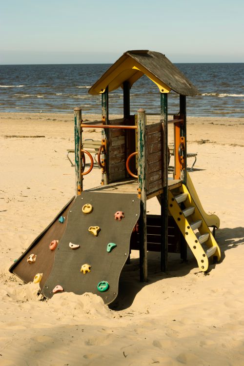 Free Children's playground with a climbing wall on a sandy beach by the sea. Stock Photo