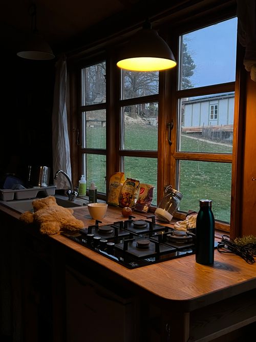 Free Warm kitchen scene at twilight with window view of a rural landscape, creating a peaceful and inviting atmosphere. Stock Photo