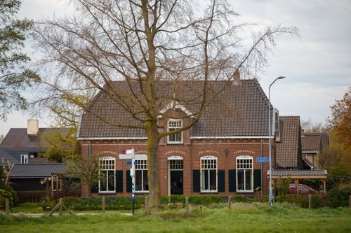 Free A picturesque Dutch rural house surrounded by budding trees in a quaint village setting. Stock Photo