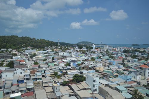 Free A scenic aerial view of a coastal city with colorful buildings and ocean in the background under a blue sky. Stock Photo