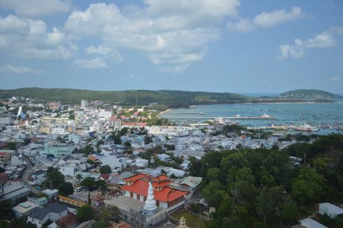 Free Aerial shot of a coastal city with a harbor, showcasing buildings, water, and greenery under a blue sky. Stock Photo
