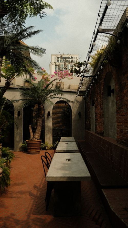 Free Inviting outdoor courtyard featuring lush greenery, rustic elements, and cozy seating. Stock Photo