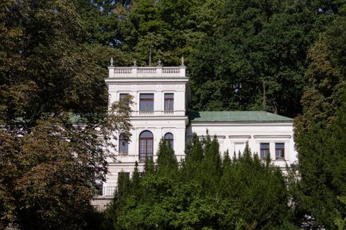 Free A classic white mansion amidst vibrant greenery under a clear sky, captured in daylight. Stock Photo