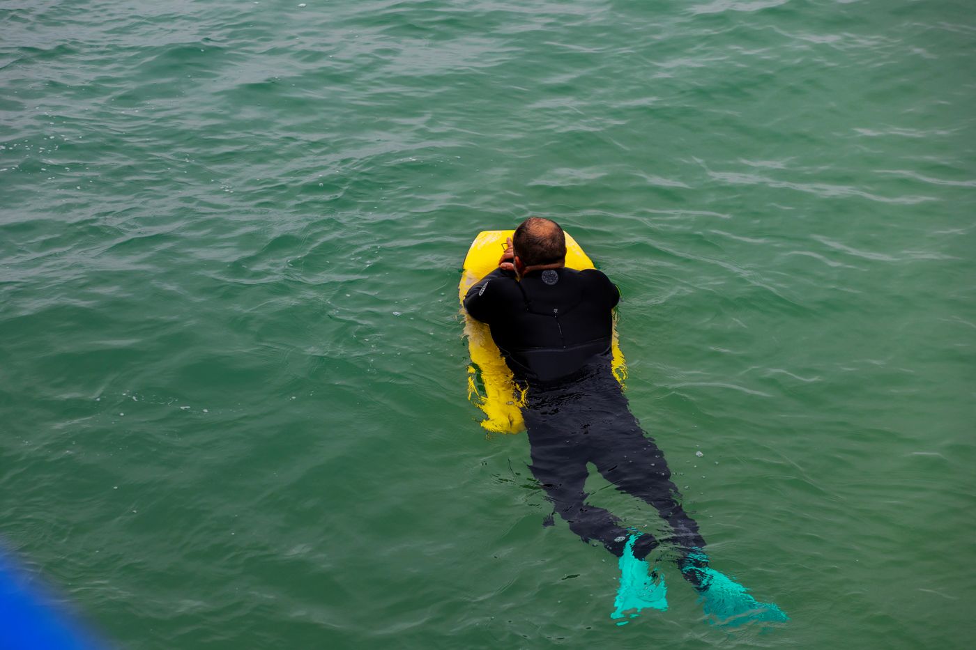 Open-water snorkeler using fins and a bright visibility float