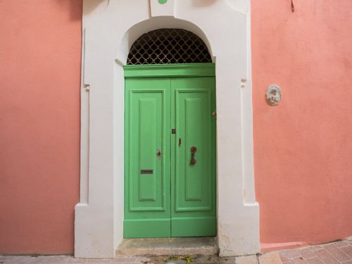 Free Bright green door set against a pink wall, typical Maltese architecture. Ideal for travel and culture themes. Stock Photo