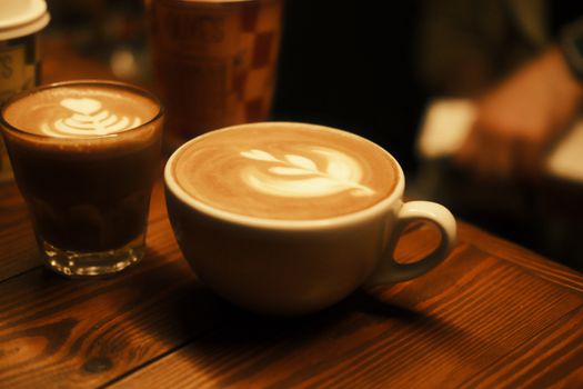 Inviting cups of coffee with intricate latte art on a cozy wooden table setting.