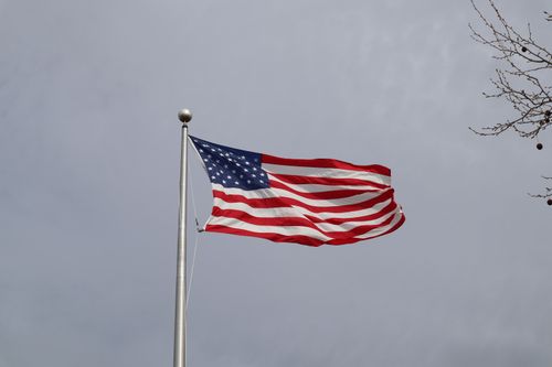 Free An American flag waves against a cloudy sky, symbolizing patriotism and national pride. Stock Photo