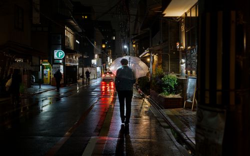 Free A man with an umbrella walks down a rainy street in Kyoto at night. Stock Photo