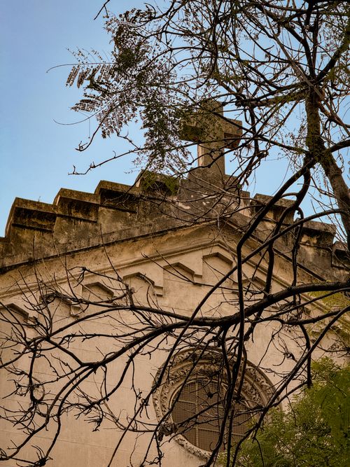 Free Gothic-style cemetery chapel with a cross atop, set against a clear sky. Stock Photo