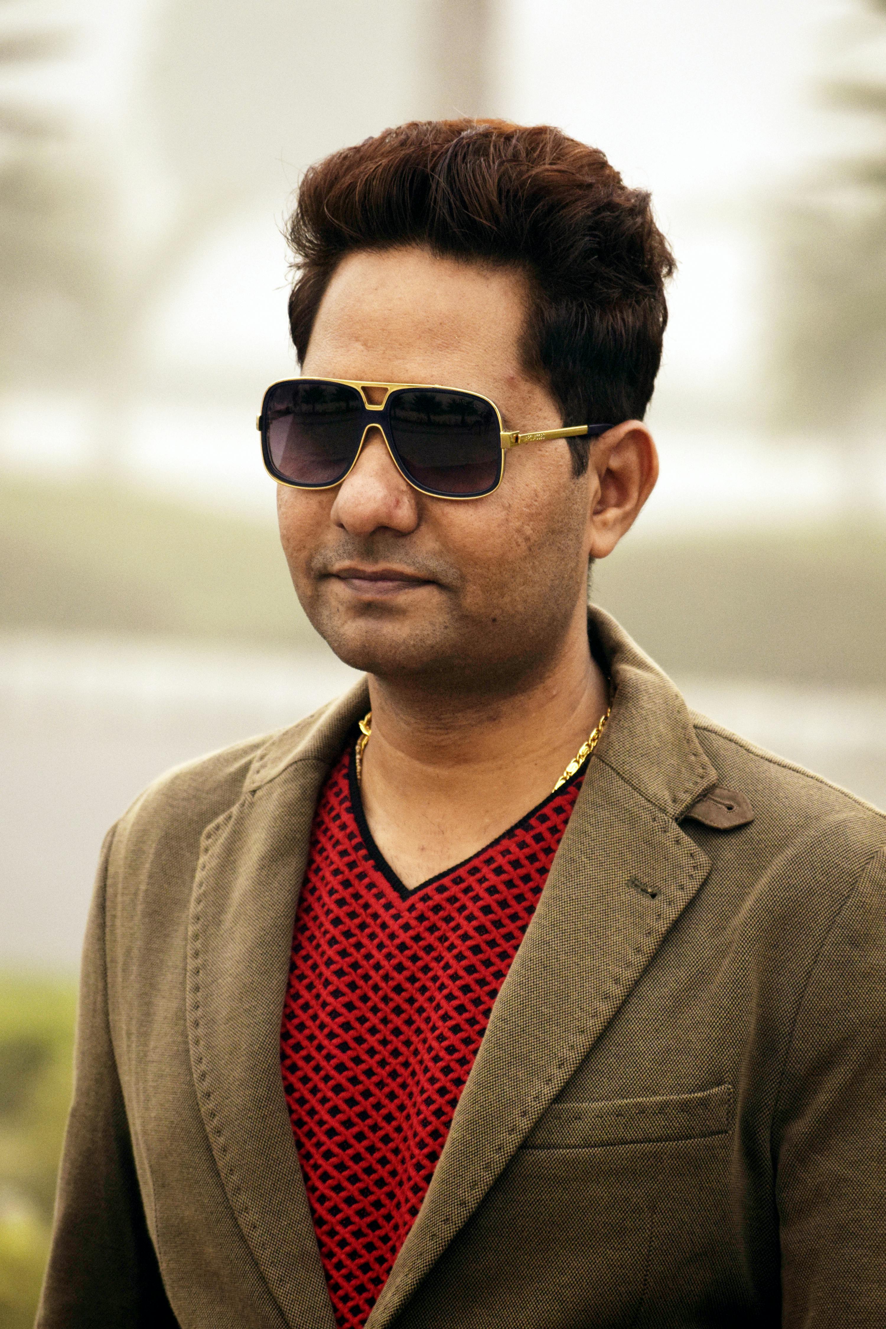 Portrait of a fashionable man wearing sunglasses and a jacket, outdoors.