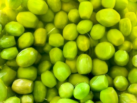 A close-up view of vibrant green olives submerged in oil, showcasing their rich color and smooth texture.