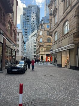 A lively shopping street in Germany featuring modern architecture with people bustling about.