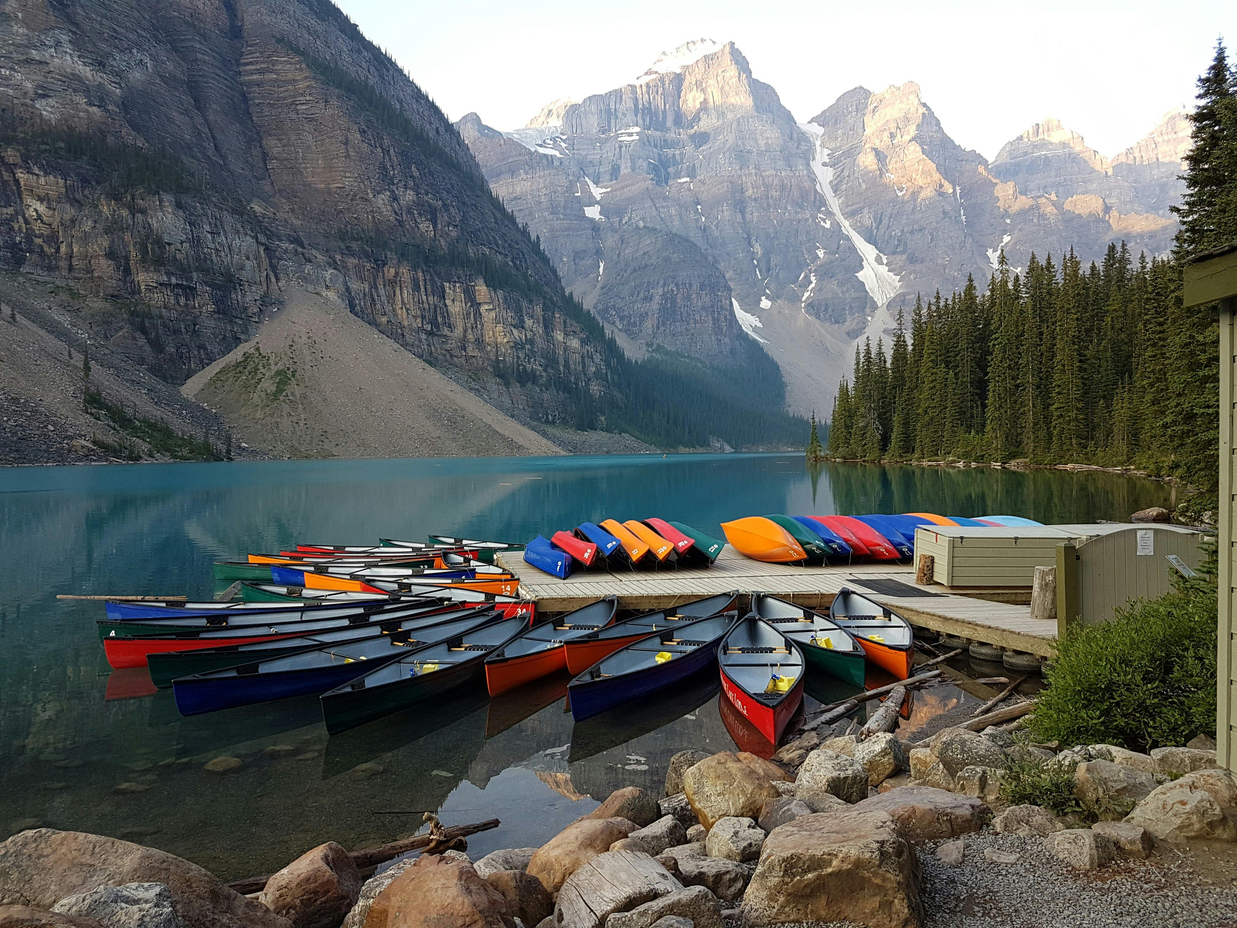 Vibrant canoes on tranquil Moraine Lake with Rocky Mountains view in Banff National Park.