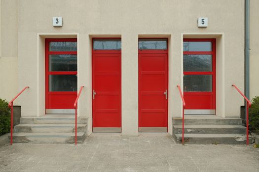 A facade with three vibrant red doors and numbered entrances, located in Berlin.