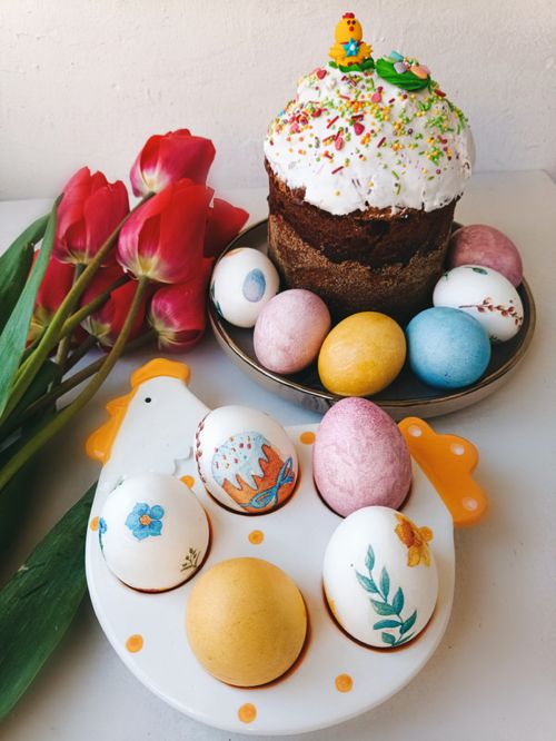 Free Decoratively painted Easter eggs with cake and red tulips create a festive spring scene. Stock Photo
