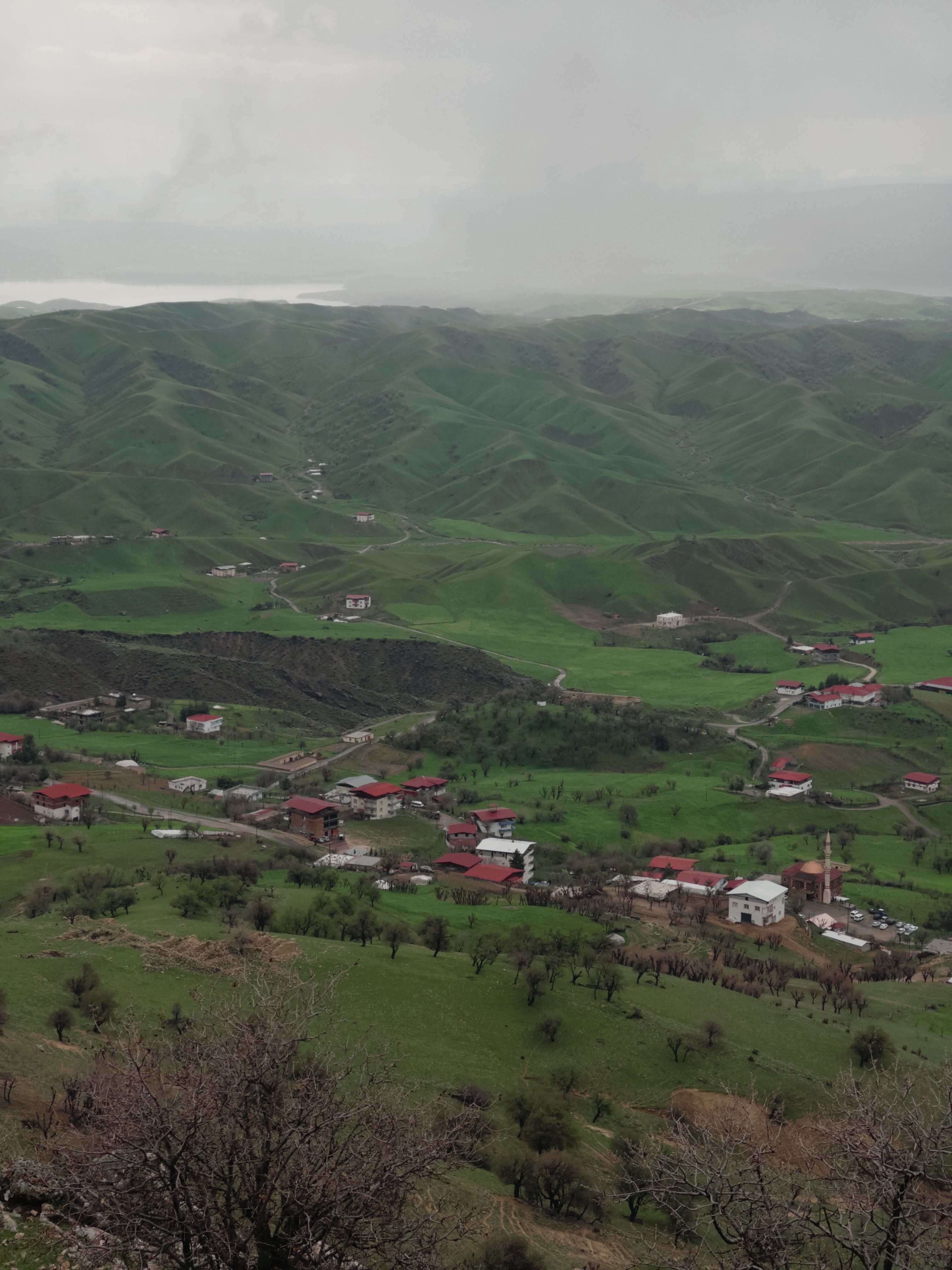 Lush green landscape of Kayar village with red-roofed buildings in spring.