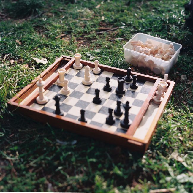 Strategic chess game set up on grass in Lisbon park, capturing a moment of outdoor relaxation.