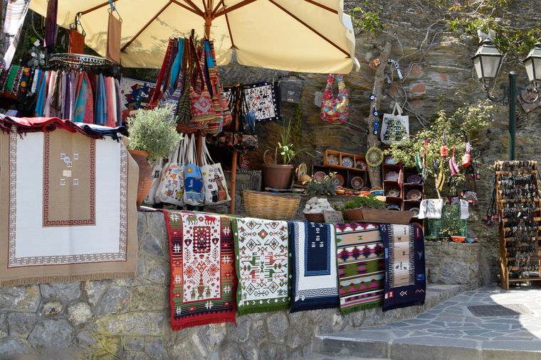 Outdoor market stall stacked with woven textiles and rugs — photo by Kimmo Vainio on Pexels