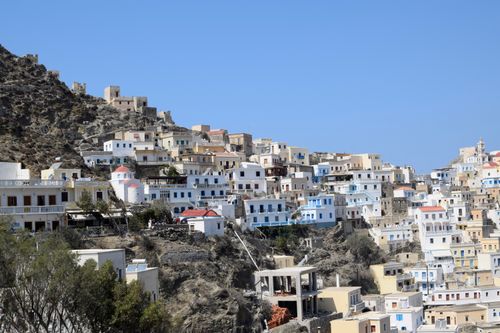 Free A picturesque hillside village in Greece with traditional architecture under a clear blue sky. Stock Photo