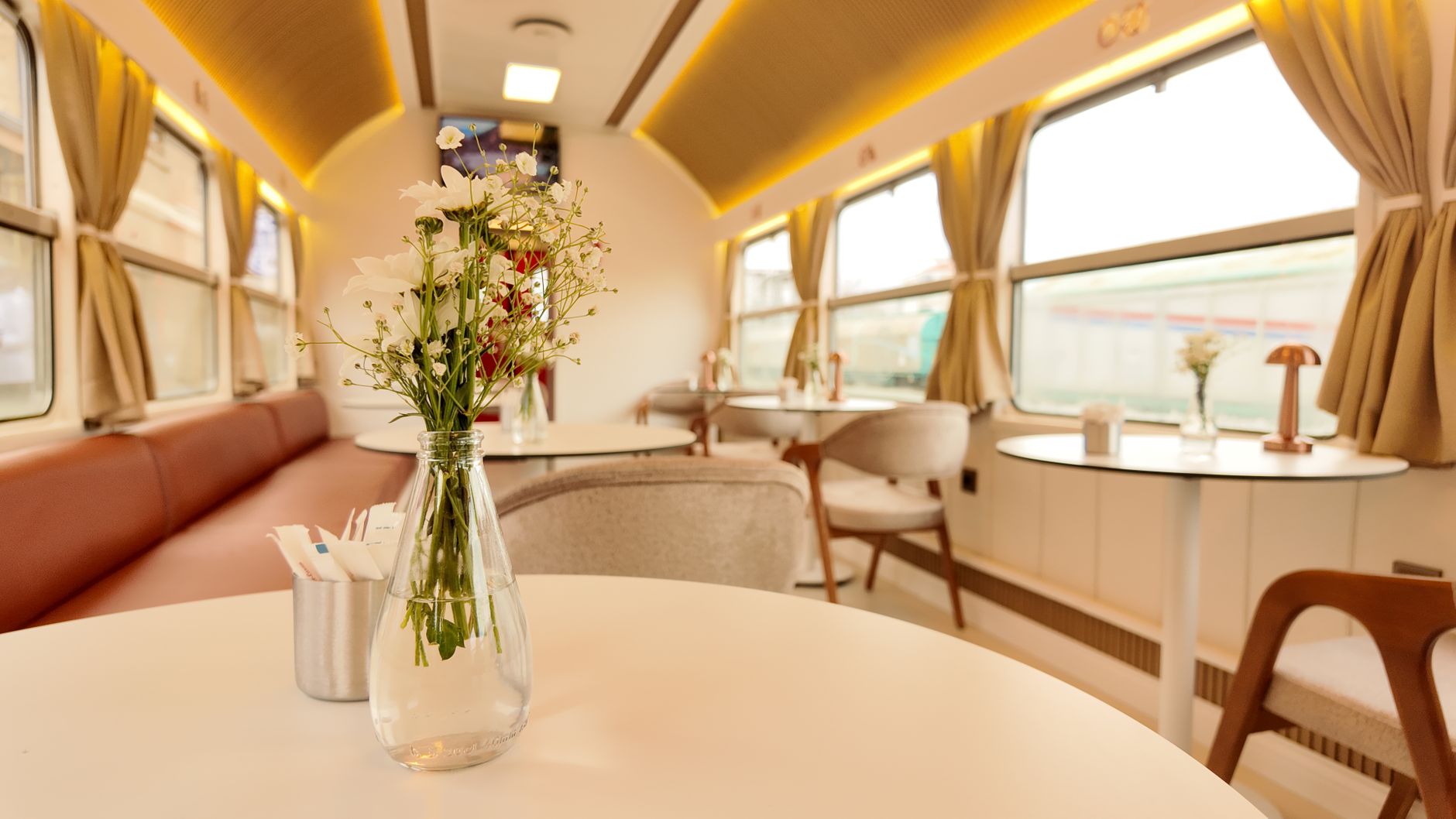 Charming interior of a vintage train dining car with floral decor creating a warm atmosphere.