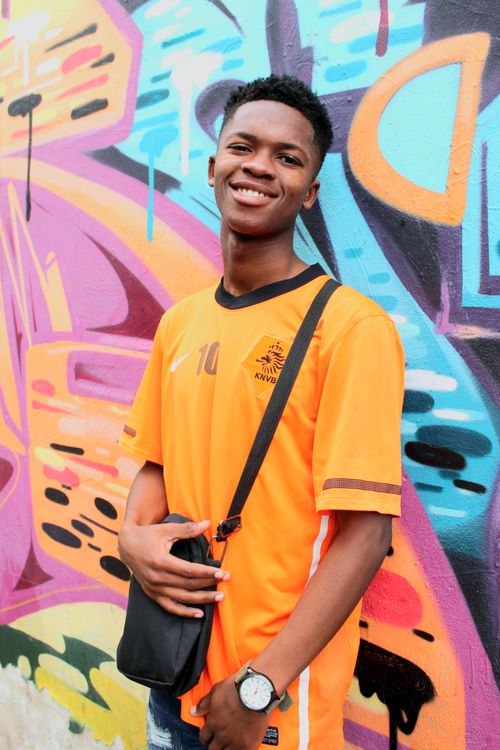 Free A smiling young man poses confidently against a colorful graffiti mural. Urban youth culture in Johannesburg. Stock Photo