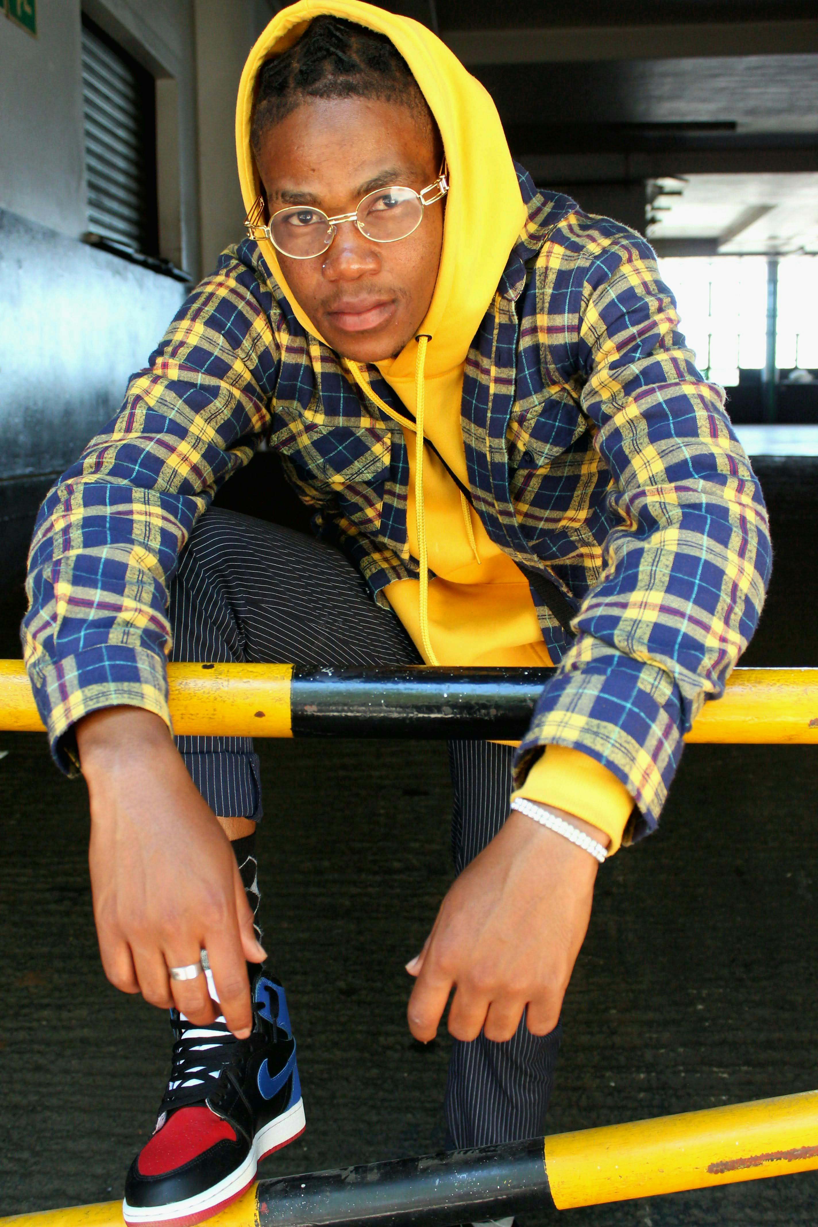 Stylish young adult in trendy streetwear leaning on a railing indoors.