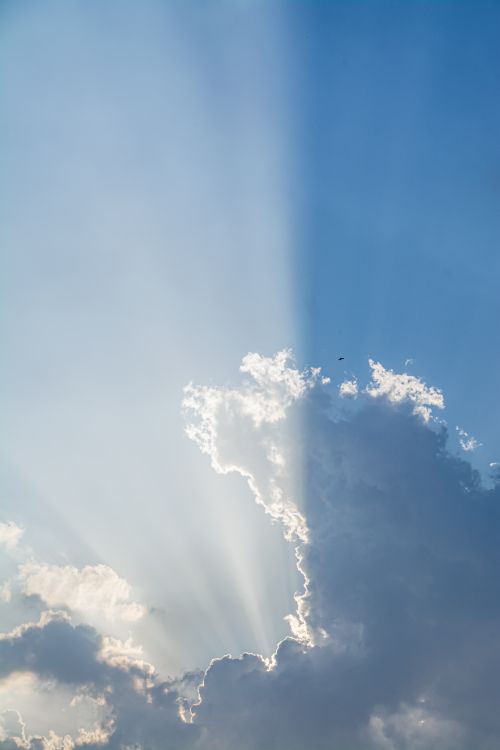 Free Captivating view of sun rays piercing through cumulus clouds in a clear blue sky. Stock Photo