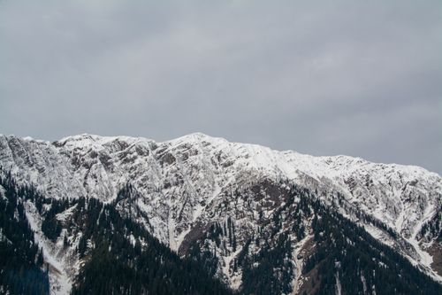 Free Stunning view of snow-covered mountain ranges under a cloudy sky, showcasing winter's beauty. Stock Photo
