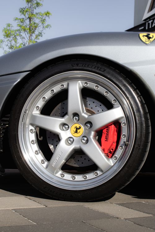 Free Detailed shot of a luxury sports car wheel with alloy rims and red brake caliper. Stock Photo