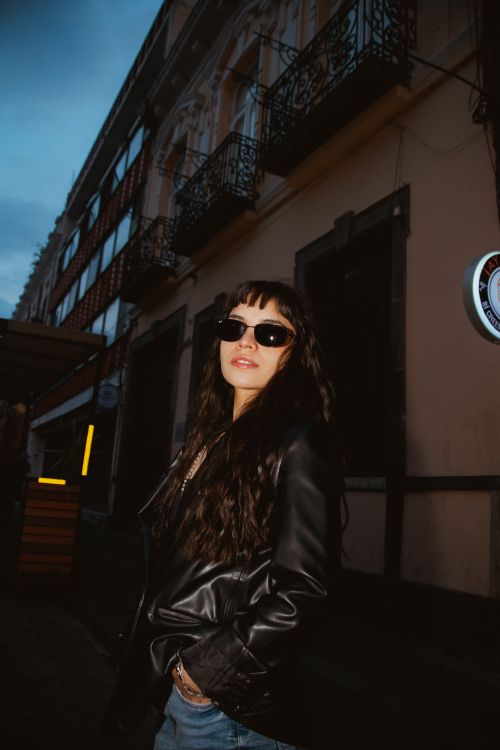 Free Fashionable woman in sunglasses and leather jacket in urban evening setting. Stock Photo