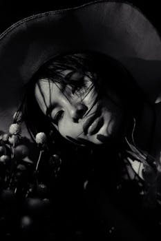 一幅黑白艺术肖像，描绘了一位戴帽子的女人，带有戏剧性的阴影