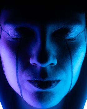 Close-up of a person's face with artistic blue and purple lighting, evoking a futuristic atmosphere.