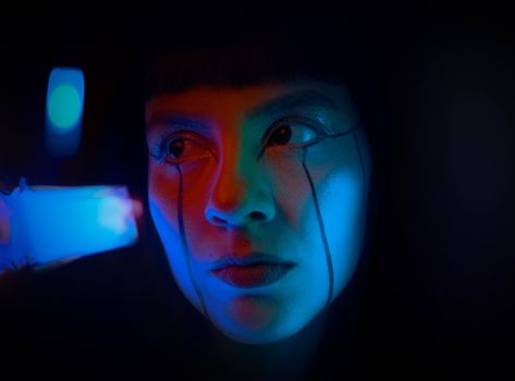 Close-up futuristic portrait with neon lighting and artistic makeup, capturing an imaginative and bold aesthetic.