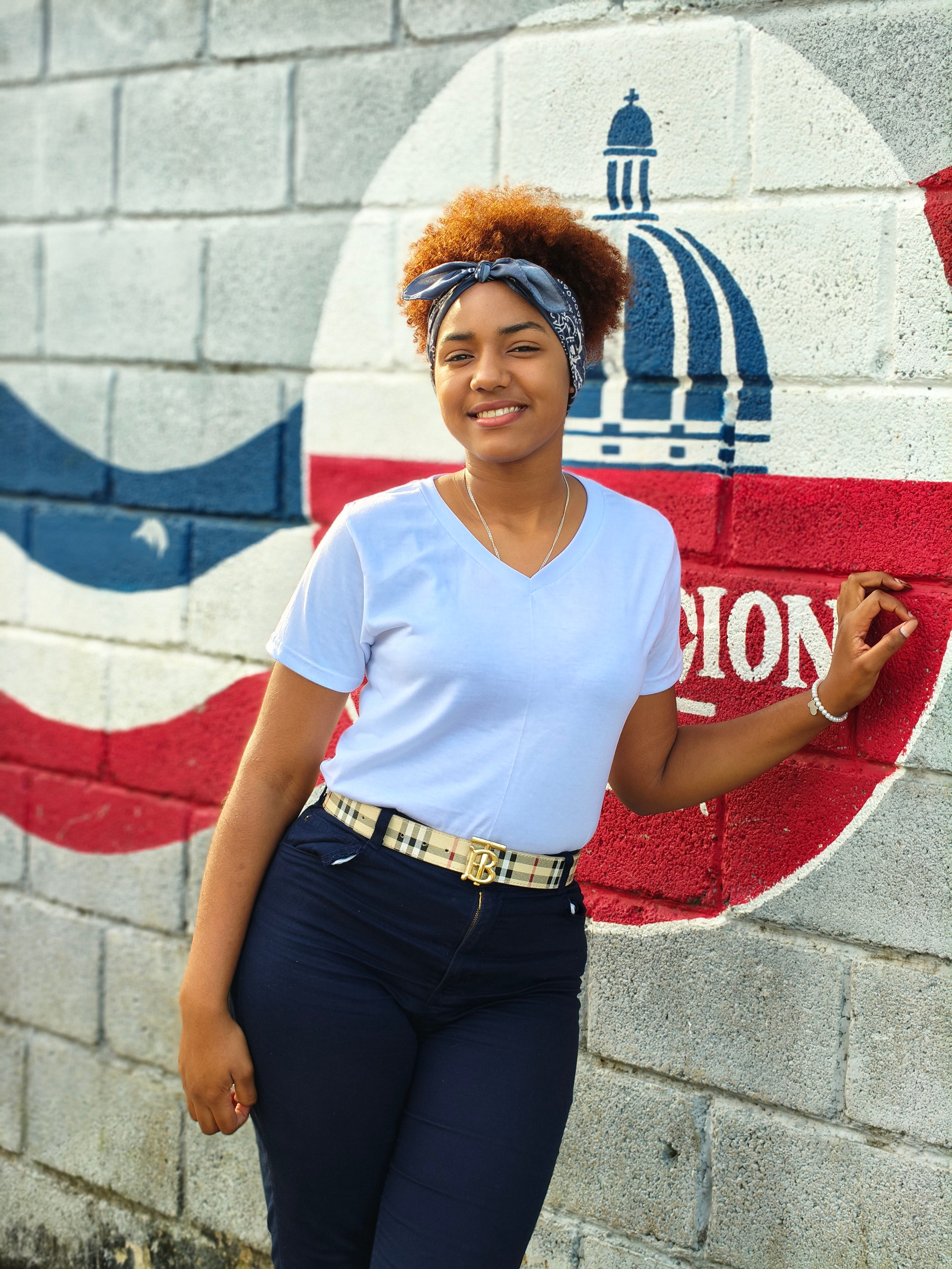 Confident young woman standing against a vibrant mural with a dome illustration, expressing joy and style.
