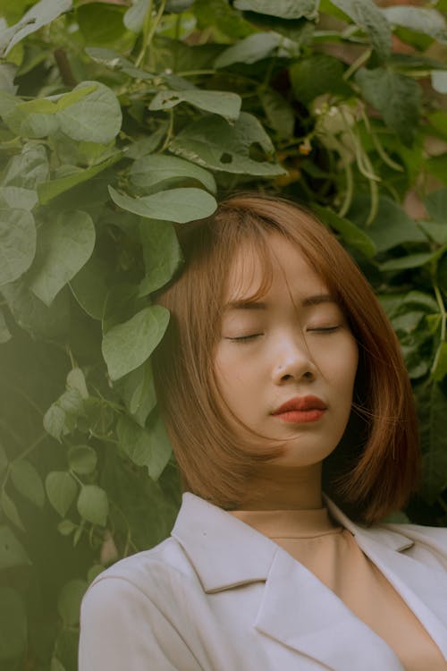 Woman with her Eyes Closed Beside Plants