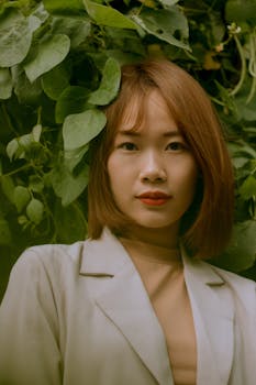 在中国青海，一位亚洲妇女的优雅肖像被郁郁葱葱的绿叶环绕