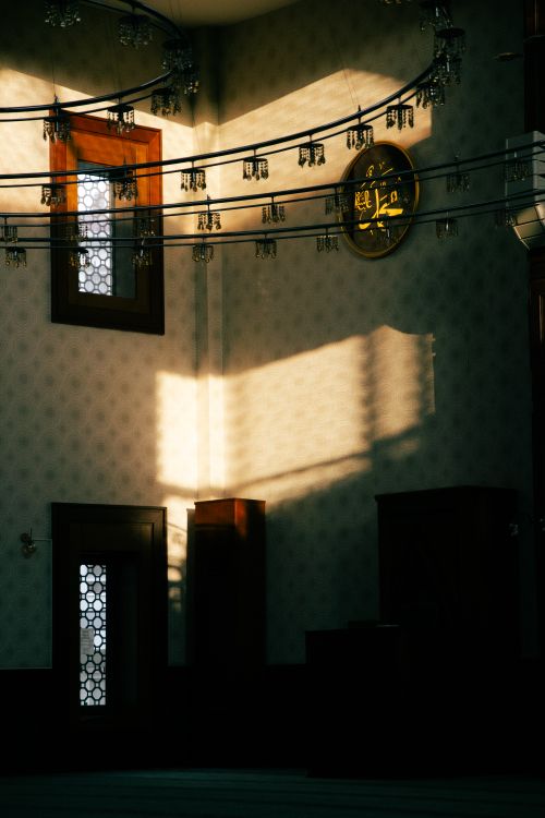 Free A serene view of sunlight casting shadows inside a mosque, highlighting intricate decor. Stock Photo
