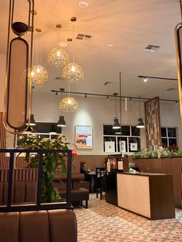 A chic and modern restaurant interior featuring unique lighting, plants, and stylish decor.
