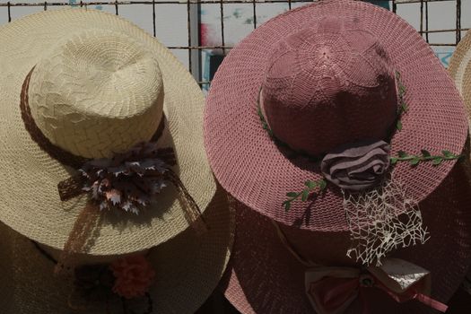 A collection of stylish straw hats with decorative flowers, displayed on a market stand.